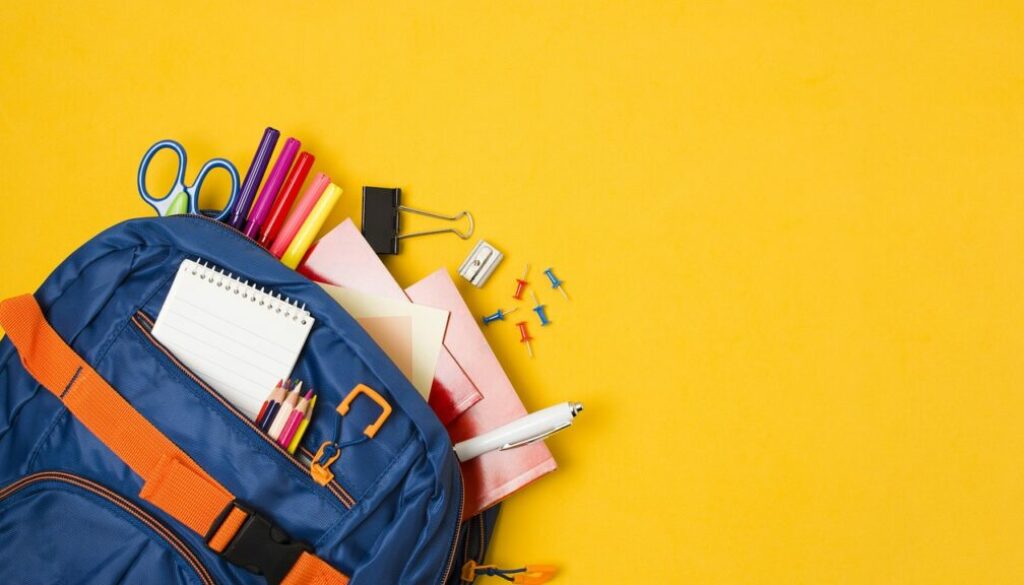 Niebieski plecak z przyborami szkolnymi na żółtym tle