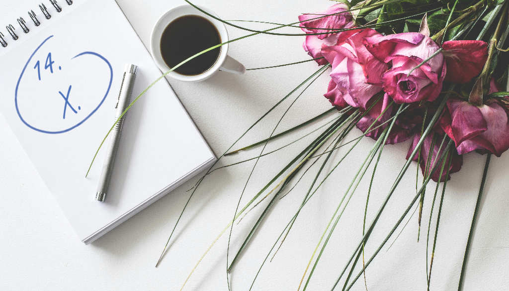 Bukiet kwiatów, długopis i notatnik z datą 14.10, filiżanka kawy