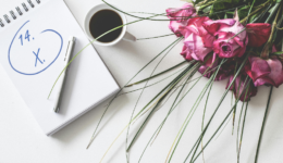 Bukiet kwiatów, długopis i notatnik z datą 14.10, filiżanka kawy